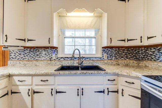 kitchen with light stone counters, sink, white cabinets, and tasteful backsplash