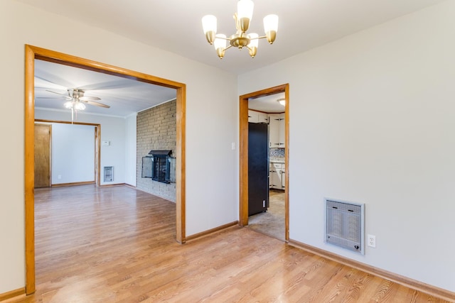 interior space featuring heating unit, ceiling fan with notable chandelier, and light hardwood / wood-style floors