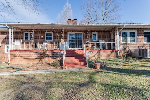 rear view of house with covered porch, a yard, and central air condition unit