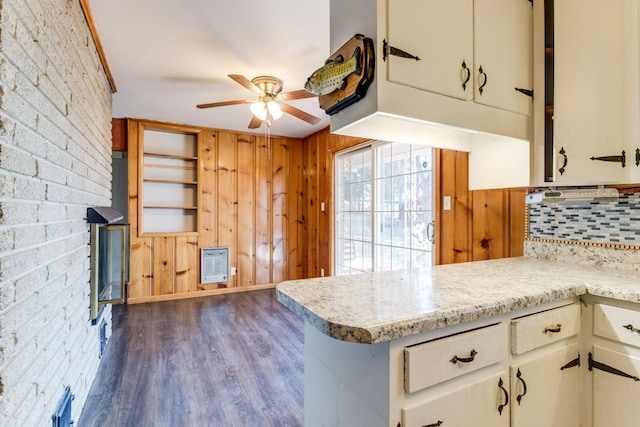 kitchen featuring kitchen peninsula, brick wall, heating unit, dark hardwood / wood-style flooring, and white cabinets