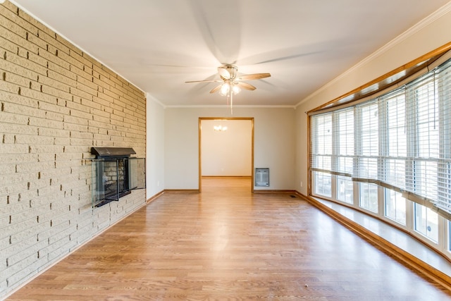 unfurnished living room with brick wall, ornamental molding, light wood-type flooring, ceiling fan, and heating unit