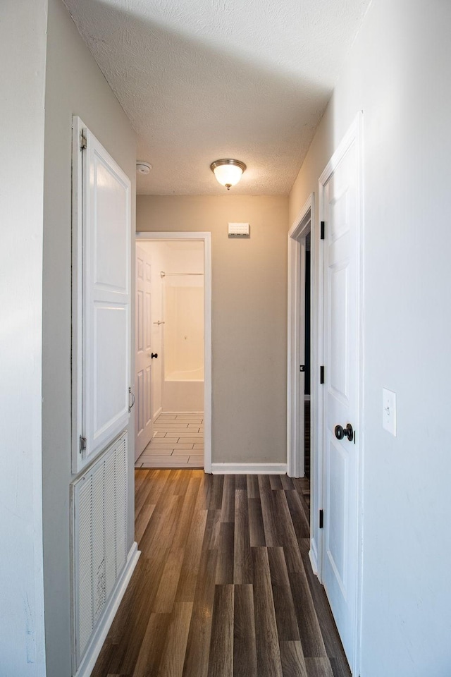 hallway featuring dark wood-type flooring and a textured ceiling