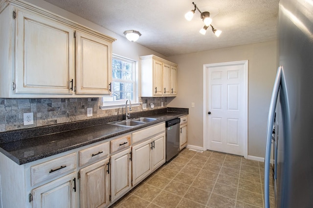 kitchen with sink, appliances with stainless steel finishes, backsplash, cream cabinets, and a textured ceiling