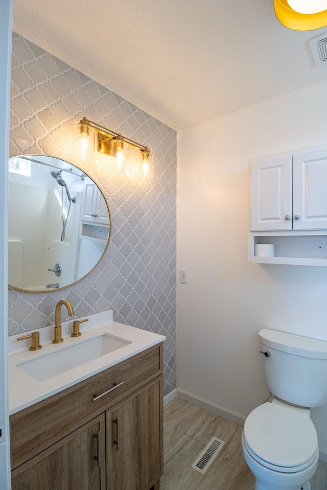 bathroom featuring hardwood / wood-style flooring, vanity, a shower, and toilet