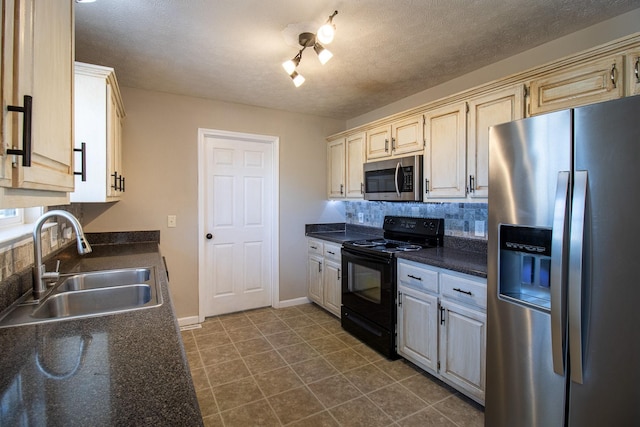 kitchen with sink, tasteful backsplash, dark tile patterned floors, stainless steel appliances, and cream cabinetry