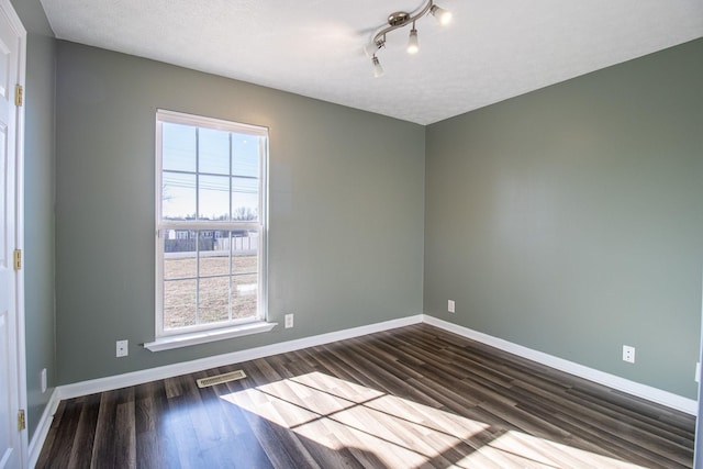 unfurnished room with a textured ceiling and dark hardwood / wood-style flooring