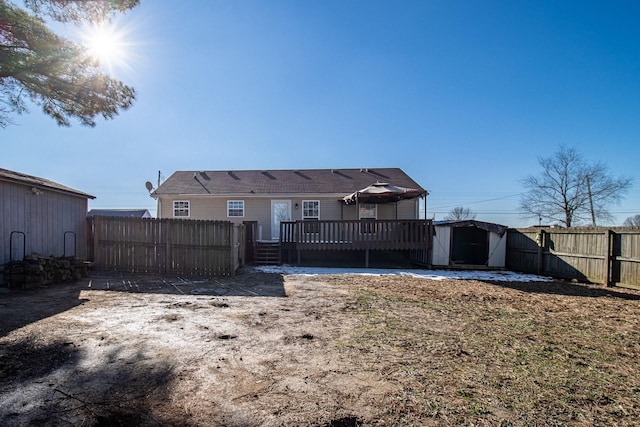 rear view of property with a deck and a storage shed