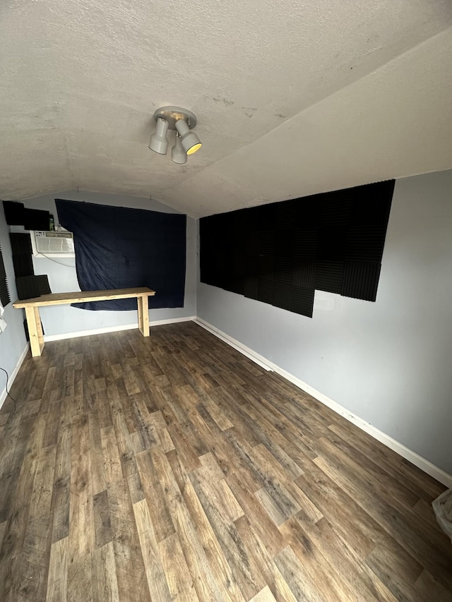 additional living space featuring lofted ceiling, hardwood / wood-style floors, and a textured ceiling