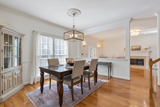 dining area with ornamental molding, light hardwood / wood-style floors, and a chandelier