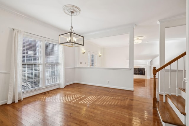 unfurnished dining area featuring crown molding, a chandelier, and hardwood / wood-style flooring