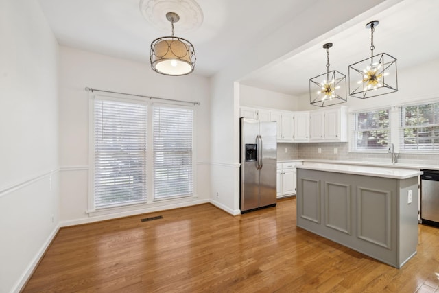 kitchen featuring stainless steel appliances, pendant lighting, white cabinetry, and a center island