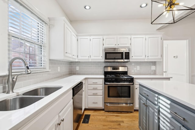 kitchen with stainless steel appliances, light hardwood / wood-style floors, white cabinetry, and sink