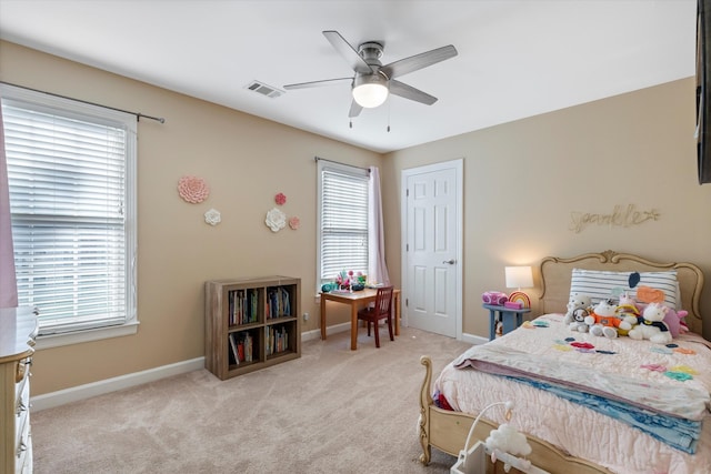 bedroom featuring ceiling fan, light colored carpet, and multiple windows