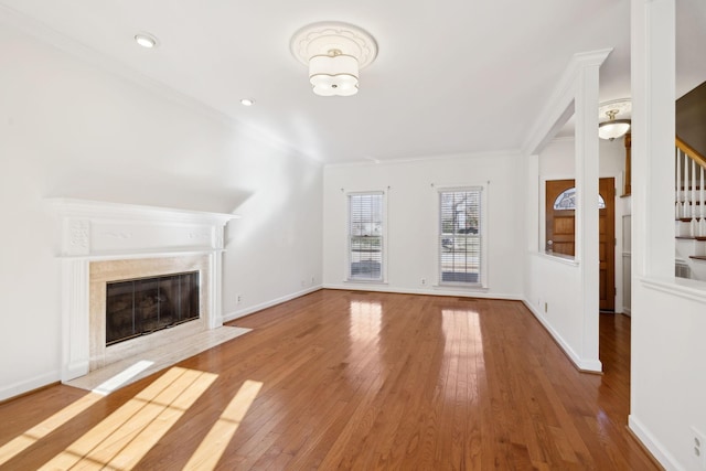 unfurnished living room with hardwood / wood-style flooring, ornamental molding, and a premium fireplace