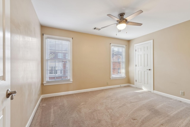 empty room with ceiling fan, plenty of natural light, and light colored carpet