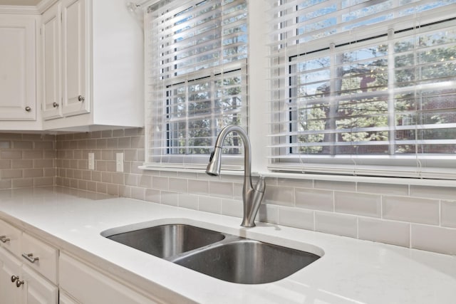 kitchen featuring a healthy amount of sunlight, white cabinets, tasteful backsplash, and sink