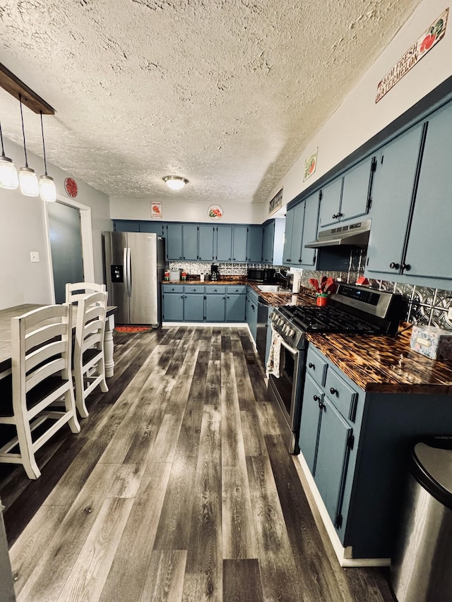 kitchen with decorative light fixtures, appliances with stainless steel finishes, blue cabinetry, and dark hardwood / wood-style floors