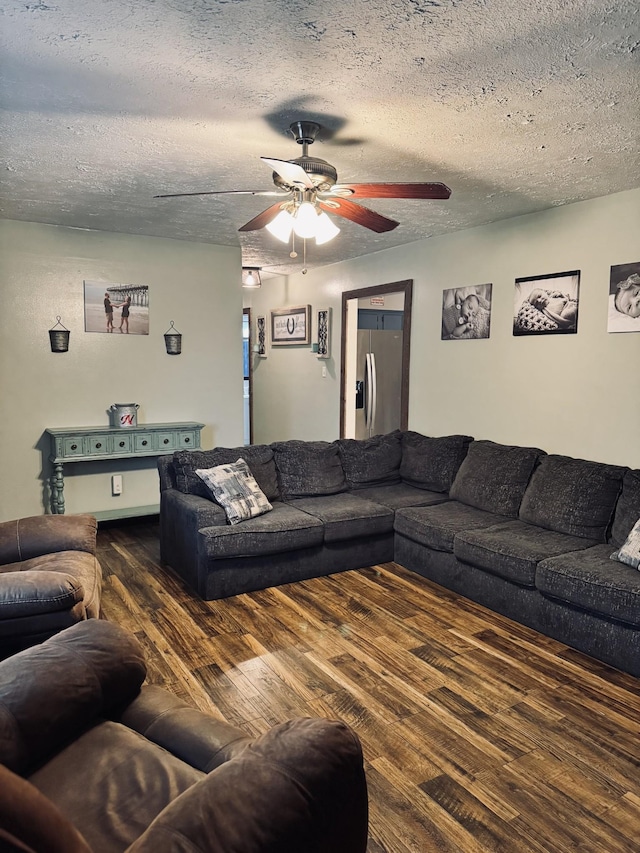 living room with a textured ceiling, ceiling fan, and dark hardwood / wood-style flooring