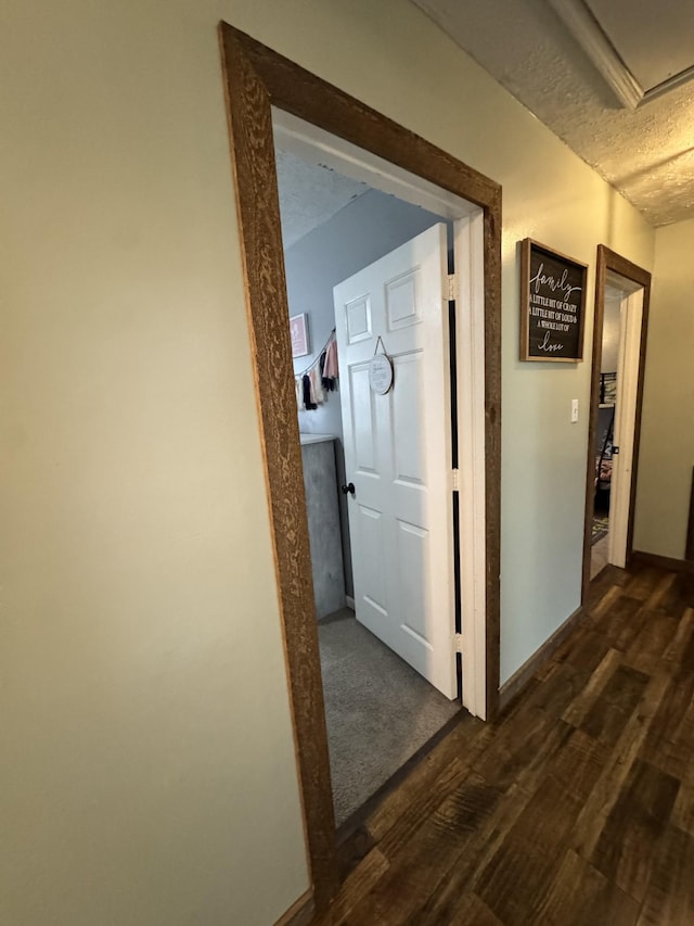 corridor with a textured ceiling and dark hardwood / wood-style floors