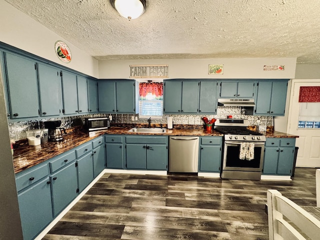 kitchen with a textured ceiling, stainless steel appliances, blue cabinets, and sink