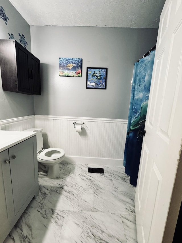 bathroom with a textured ceiling, toilet, and vanity