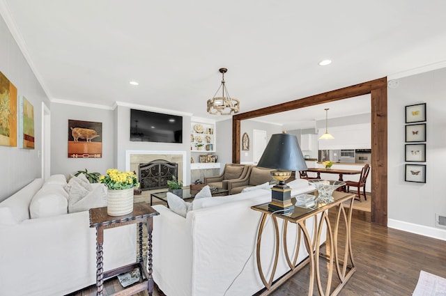 living room featuring a notable chandelier, crown molding, hardwood / wood-style flooring, built in shelves, and a high end fireplace