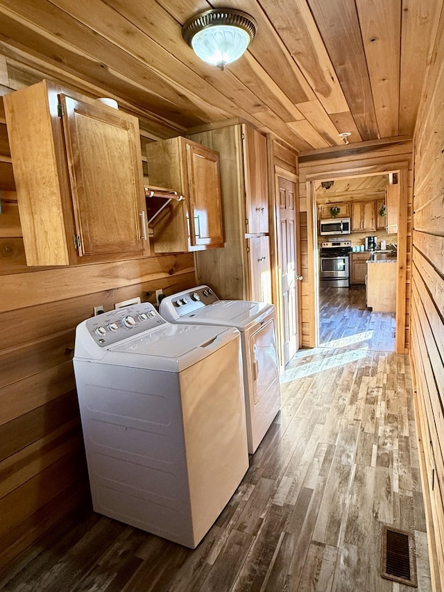 laundry area with washing machine and dryer, wood ceiling, cabinets, dark hardwood / wood-style floors, and wood walls