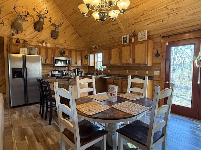 dining space featuring a healthy amount of sunlight, vaulted ceiling, an inviting chandelier, and wooden ceiling