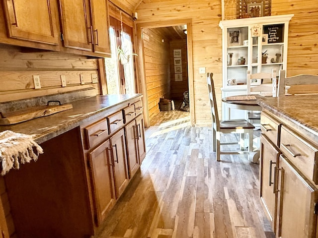 kitchen featuring light hardwood / wood-style floors, vaulted ceiling, and wooden walls