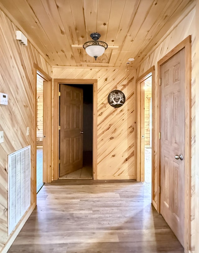 hallway featuring wood ceiling, wood walls, and hardwood / wood-style floors