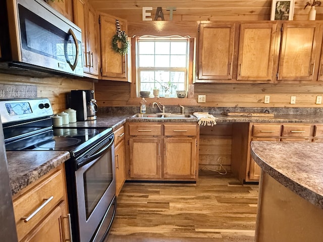 kitchen featuring light hardwood / wood-style floors, sink, appliances with stainless steel finishes, and wood walls