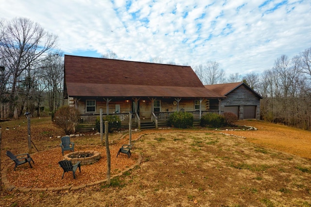 view of front of home with covered porch, a garage, a fire pit, and a front lawn