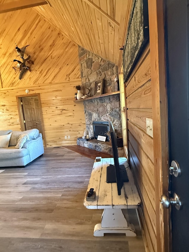 interior space with vaulted ceiling, a fireplace, wood walls, hardwood / wood-style flooring, and wood ceiling