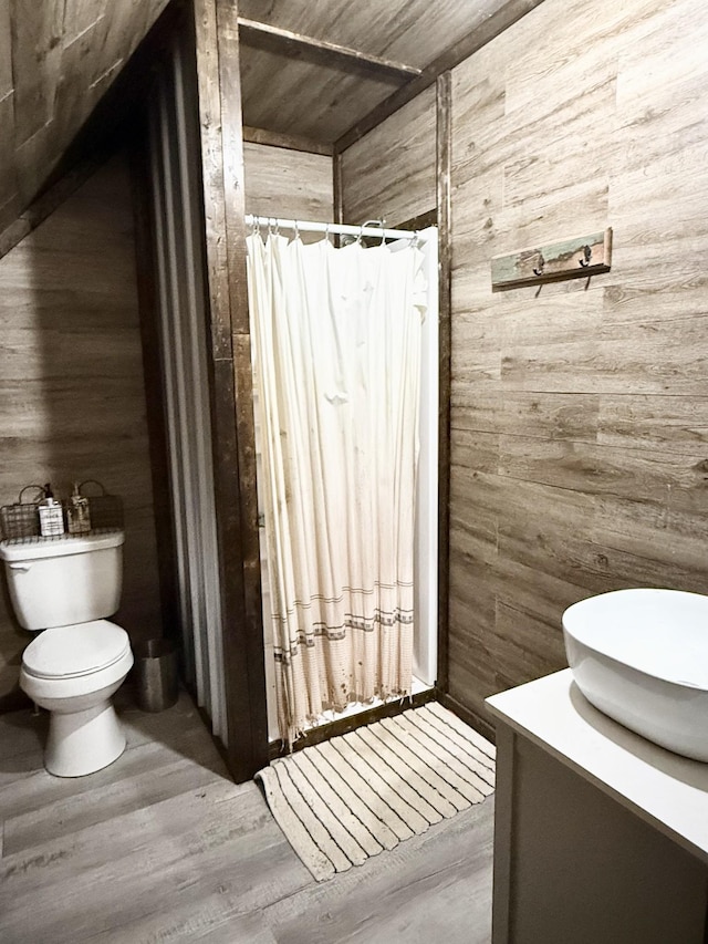 bathroom with hardwood / wood-style floors, toilet, vanity, and wooden walls