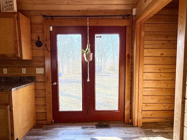 doorway to outside featuring dark hardwood / wood-style floors, a healthy amount of sunlight, and wood walls