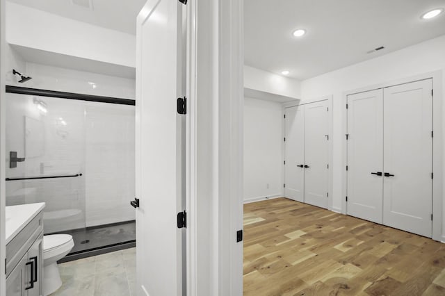 bathroom featuring toilet, a shower with shower door, wood-type flooring, and vanity