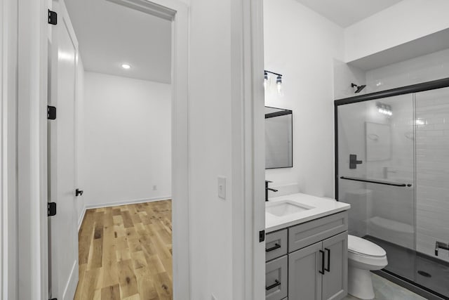 bathroom featuring toilet, walk in shower, hardwood / wood-style flooring, and vanity