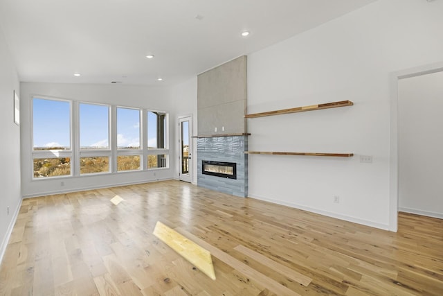 unfurnished living room with light hardwood / wood-style flooring, a tile fireplace, and vaulted ceiling