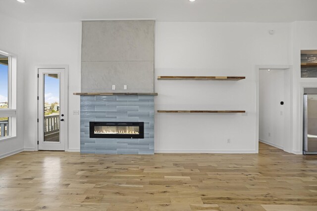 unfurnished living room with light hardwood / wood-style floors and a tiled fireplace