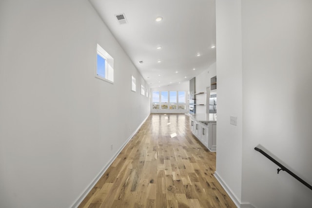 hall featuring lofted ceiling and light hardwood / wood-style floors