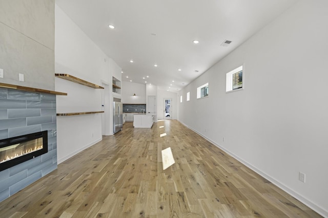 unfurnished living room featuring a fireplace, sink, and light hardwood / wood-style flooring