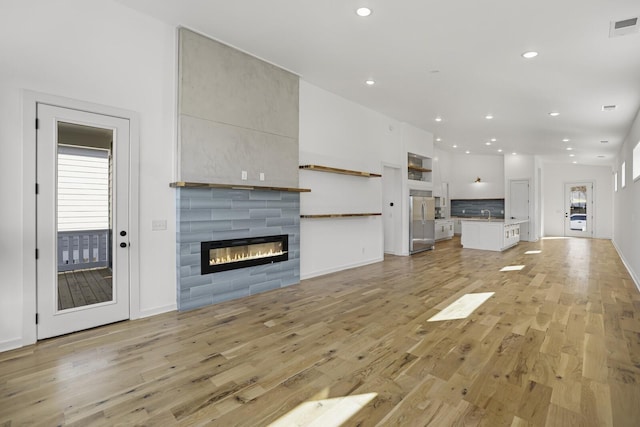 unfurnished living room featuring a tile fireplace and light hardwood / wood-style flooring