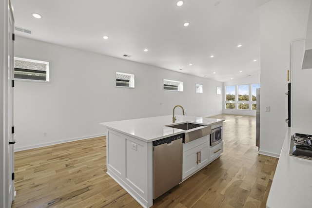 kitchen with a center island with sink, appliances with stainless steel finishes, white cabinets, light hardwood / wood-style flooring, and sink