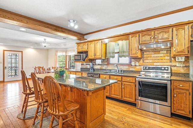 kitchen with a kitchen bar, appliances with stainless steel finishes, tasteful backsplash, a kitchen island, and sink