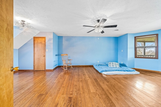 unfurnished bedroom with ceiling fan, lofted ceiling, a textured ceiling, and hardwood / wood-style flooring