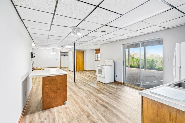 kitchen with a drop ceiling, sink, white appliances, and light hardwood / wood-style flooring