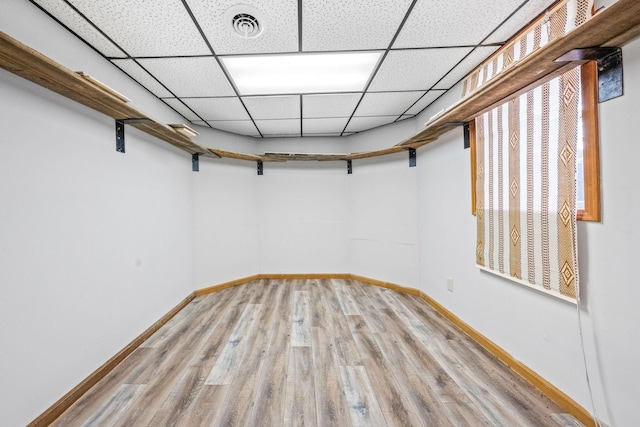 basement with light hardwood / wood-style floors and a paneled ceiling