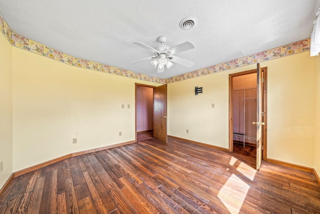 unfurnished room with ceiling fan, dark hardwood / wood-style flooring, and a textured ceiling