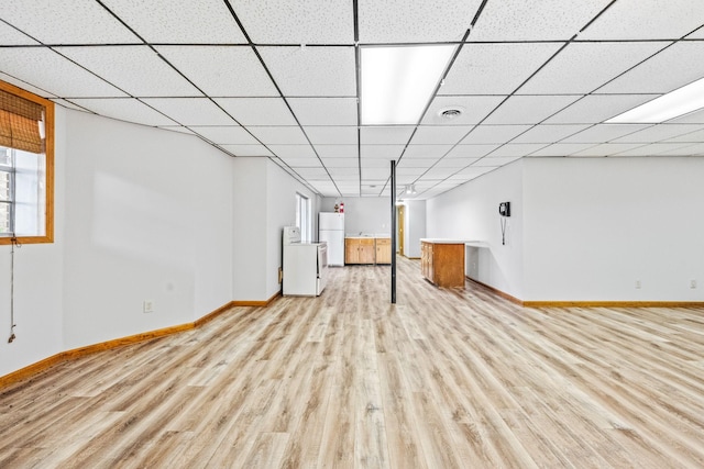 basement featuring light wood-type flooring, white refrigerator, and washer / clothes dryer