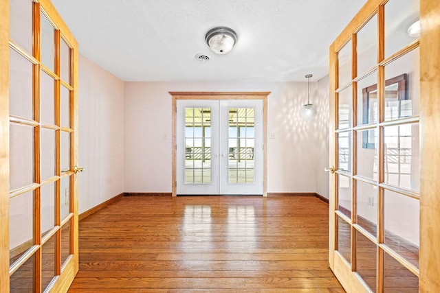 empty room with hardwood / wood-style flooring and french doors